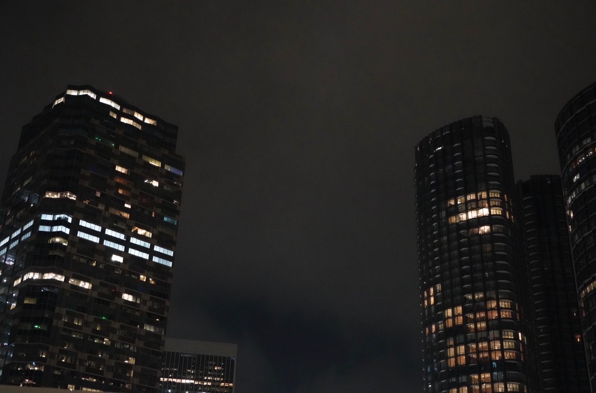 Illuminated high-rise apartment towers against the night sky.